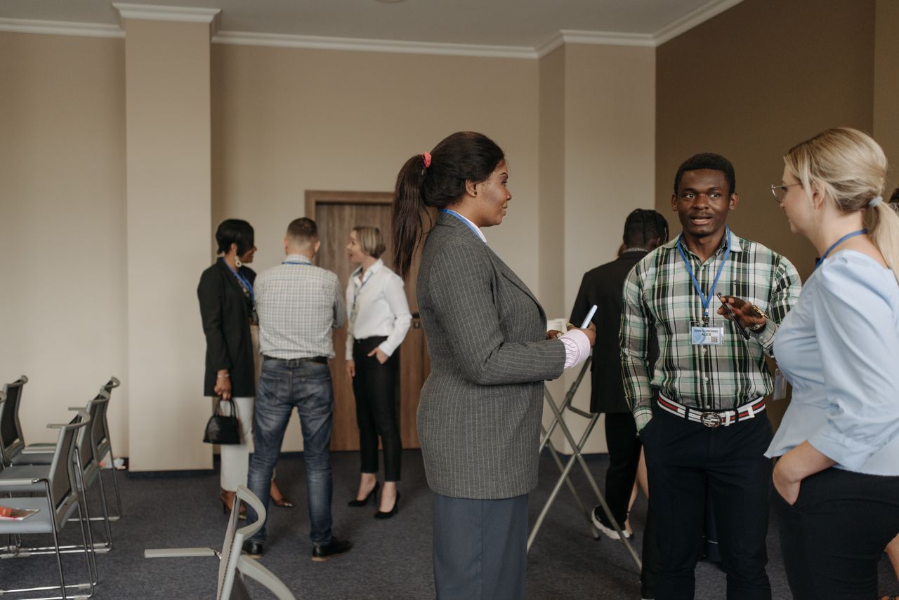services-01 Professionals engaging in conversation at a diverse business conference with corporate attire indoors.